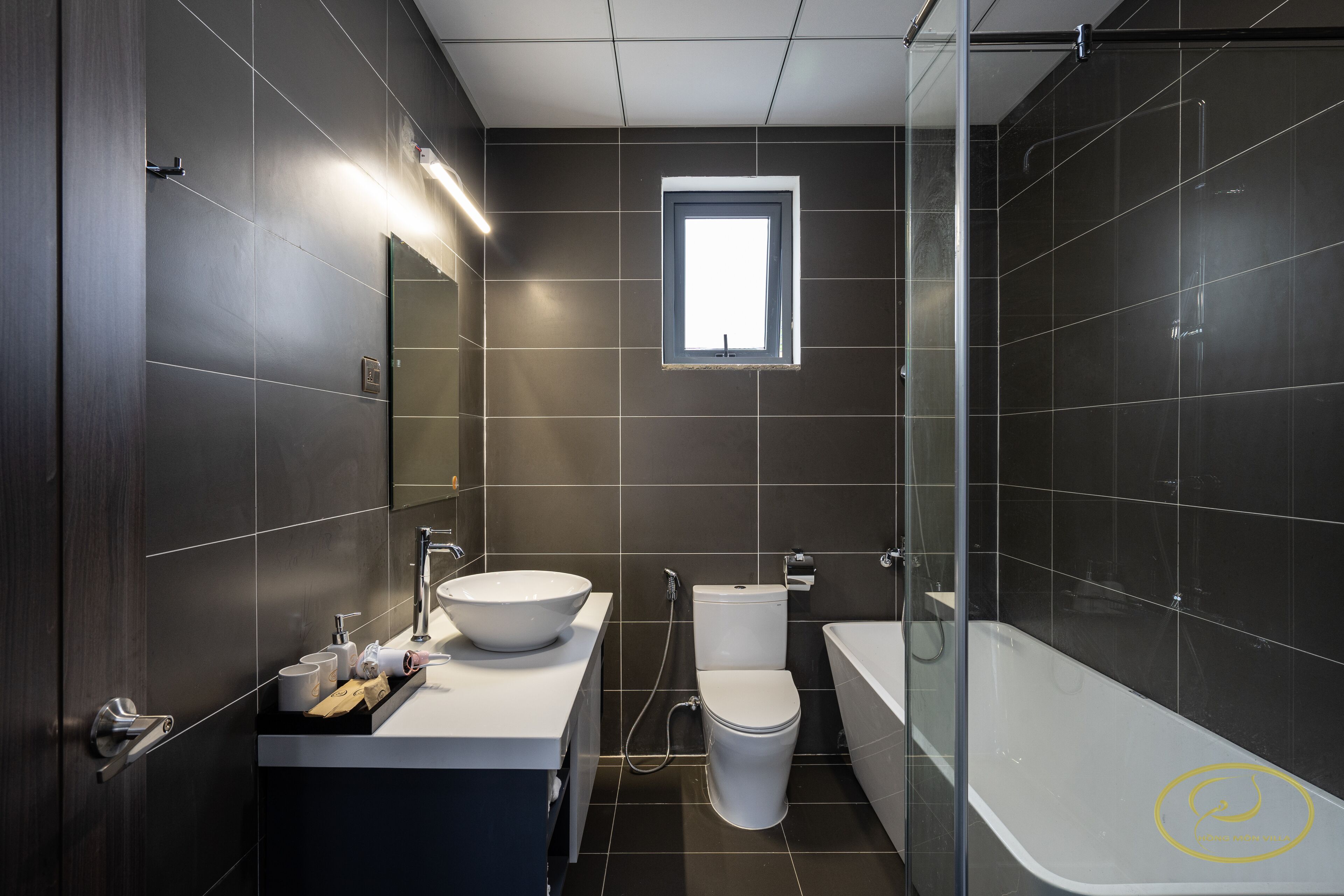 Une salle de bain moderne avec un grand miroir, un lavabo blanc, des toilettes et une baignoire.