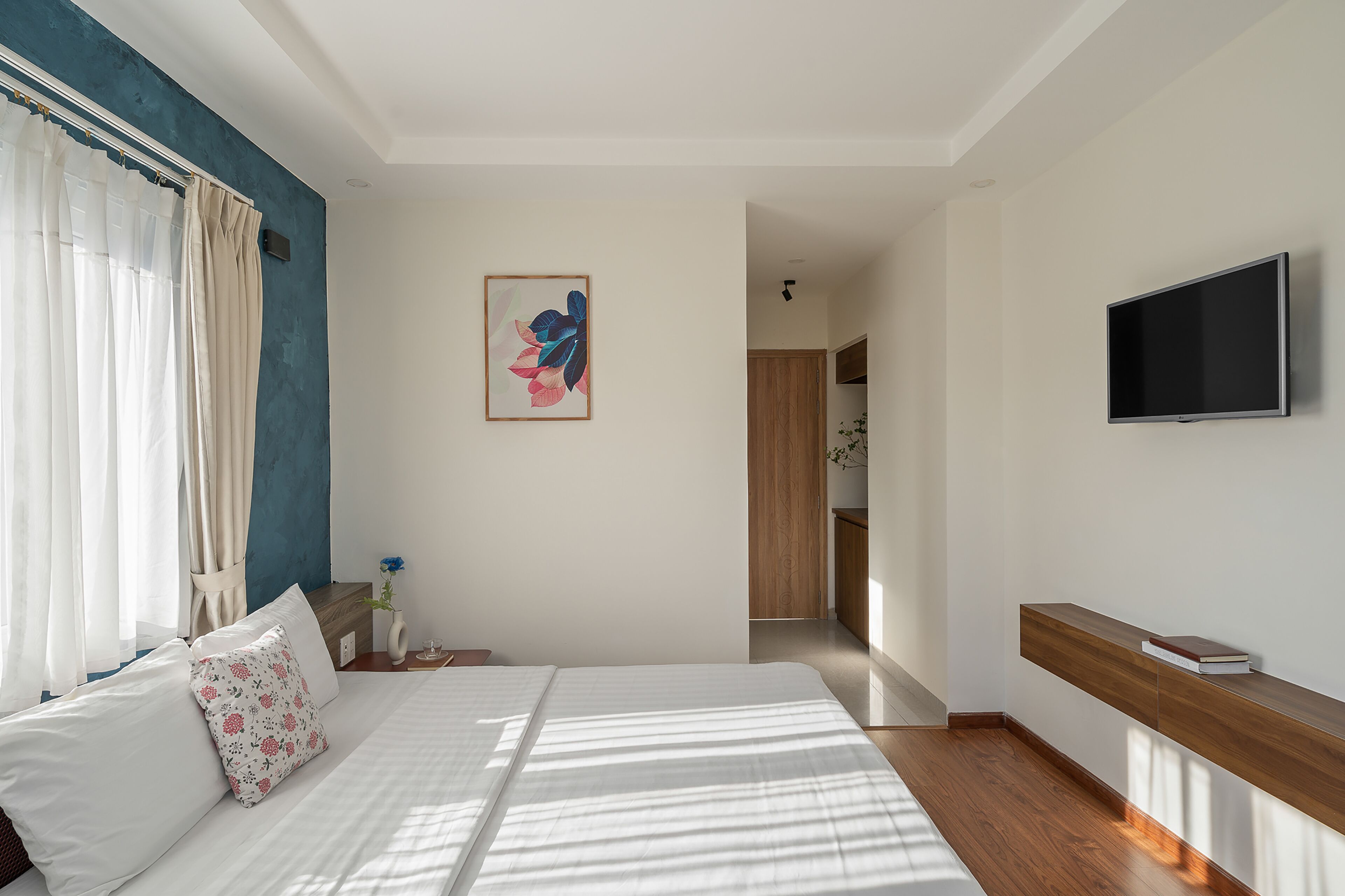 Habitación de hotel moderna con una cama grande, un televisor de pantalla plana en la pared y un banco de madera con un libro.