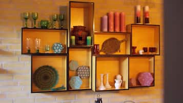 Een muur met meerdere planken waarop decoratieve objecten staan, zoals glaswerk, kaarsen en aardewerk.