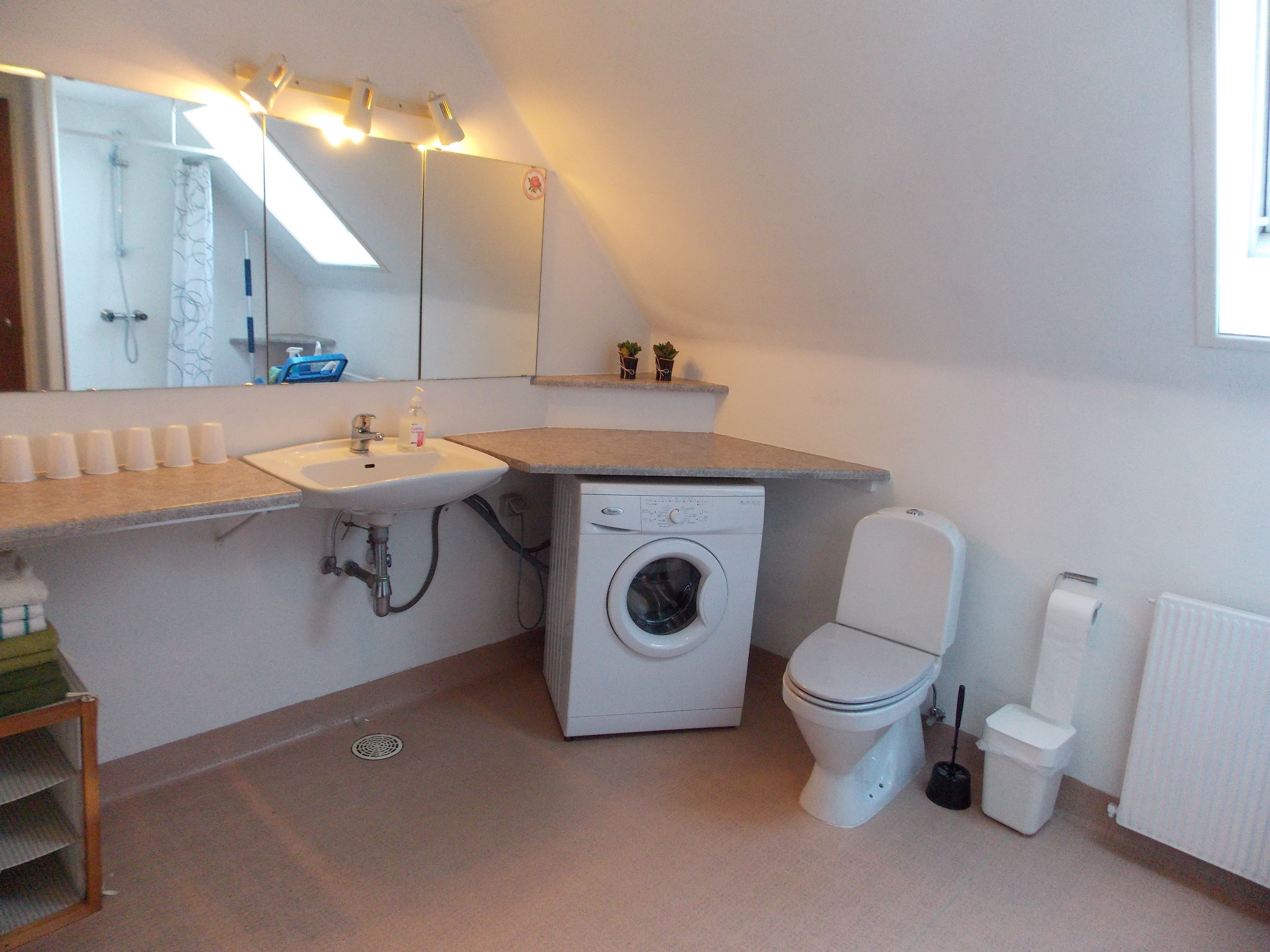 A small, modern bathroom with a sink, toilet, and washing machine.