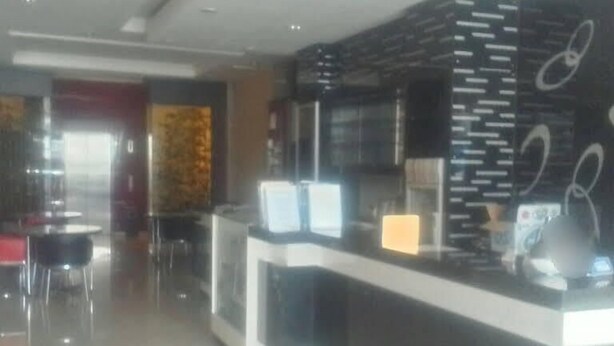 Un moderno vestíbulo de hotel con un mostrador de recepción, zona de estar y una pared decorativa.