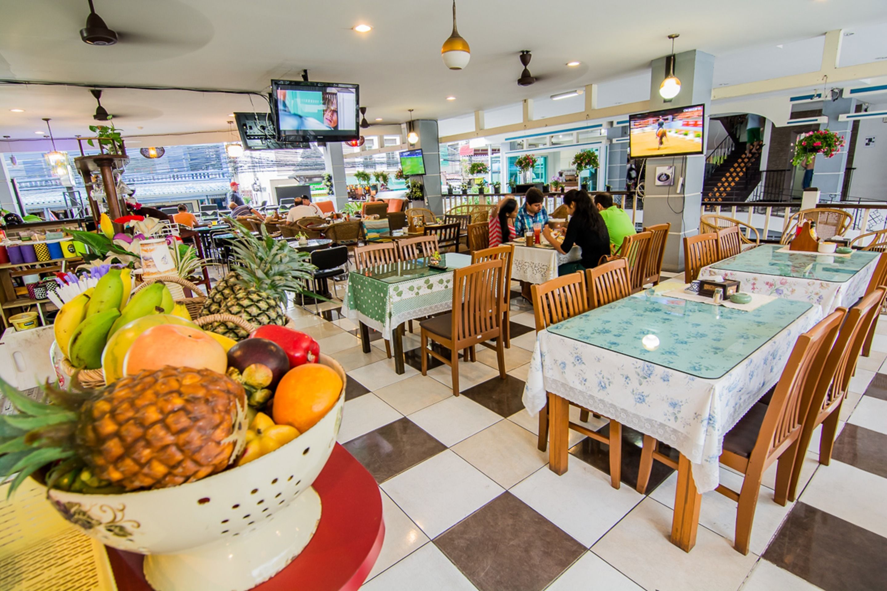 A restaurant with a checkered floor, wooden chairs, and tables with floral tablecloths.