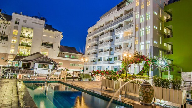 A swimming pool area with a fountain, surrounded by buildings with balconies and a green wall. - Sutus Court 1 (Pattaya)