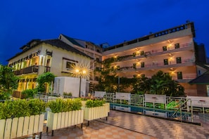 A multi-story hotel with balconies, a swimming pool, and a well-lit outdoor area. - Sutus Court 1 (Pattaya)