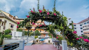 A covered outdoor area with a bench, a table, and a sign that reads "OPEN TO THE PUBLIC." - Sutus Court 1 (Pattaya)