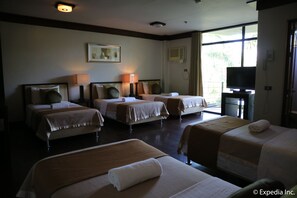 A hotel room with four beds, a television, and a large window with curtains. - Splash Suites Hotel Laguna (Los Banos)