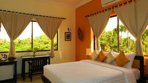 A hotel room with a bed, a desk, and a window with curtains. - Villa Nissa (Siem Reap)