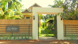 Villa Nissa Hotel & Resort entrance with a brick wall, a signboard, and a pathway leading to the building. - Villa Nissa (Siem Reap)