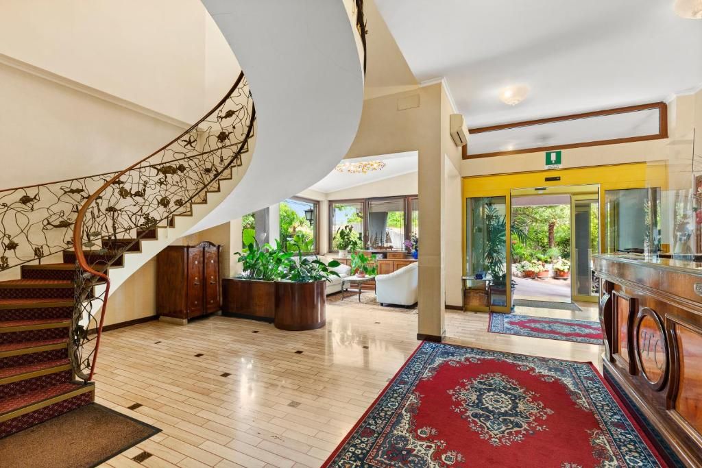 A spacious lobby with a grand staircase, a reception desk, and a view of the outdoors.