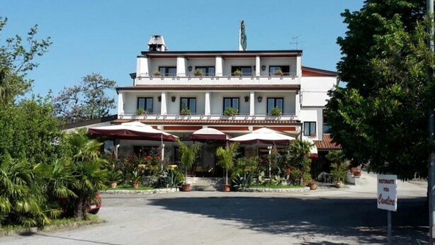 A two-story building with a white facade, multiple windows, and outdoor umbrellas.