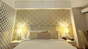 A hotel room with a large bed, two bedside tables with lamps, a decorative ceiling light, and a patterned wallpaper. - MaxStays Max Pavilion at The Venice Residences (Taguig)