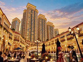 Pátio de hotel com mobiliário de exterior, um canal e edifícios altos ao fundo.