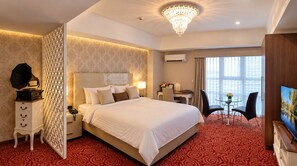 A hotel room with a large bed, a desk with a chair, a television, and a decorative wall panel. - MaxStays Max Pavilion at The Venice Residences (Taguig)