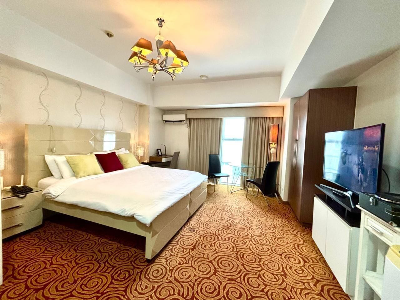 Habitación de hotel con una cama grande, televisión, escritorio y silla.