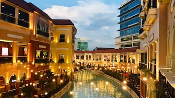 A canal with buildings on either side, featuring outdoor seating areas and illuminated windows.
