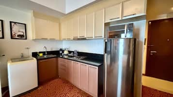 A compact kitchen with a refrigerator, microwave, sink, and a small countertop.