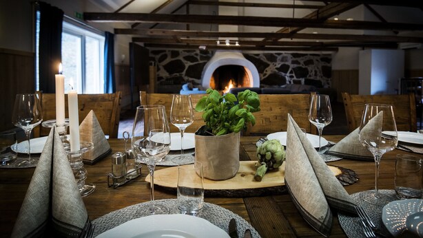 A dining table set for a meal with a stone fireplace in the background. - Stiftsgården Södra Hoka (Asarum)