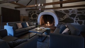 A cozy living room with a stone fireplace, wooden beams, and modern furniture. - Stiftsgården Södra Hoka (Asarum)