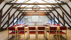 A conference room with wooden beams, a whiteboard, and red chairs. - Stiftsgården Södra Hoka (Asarum)