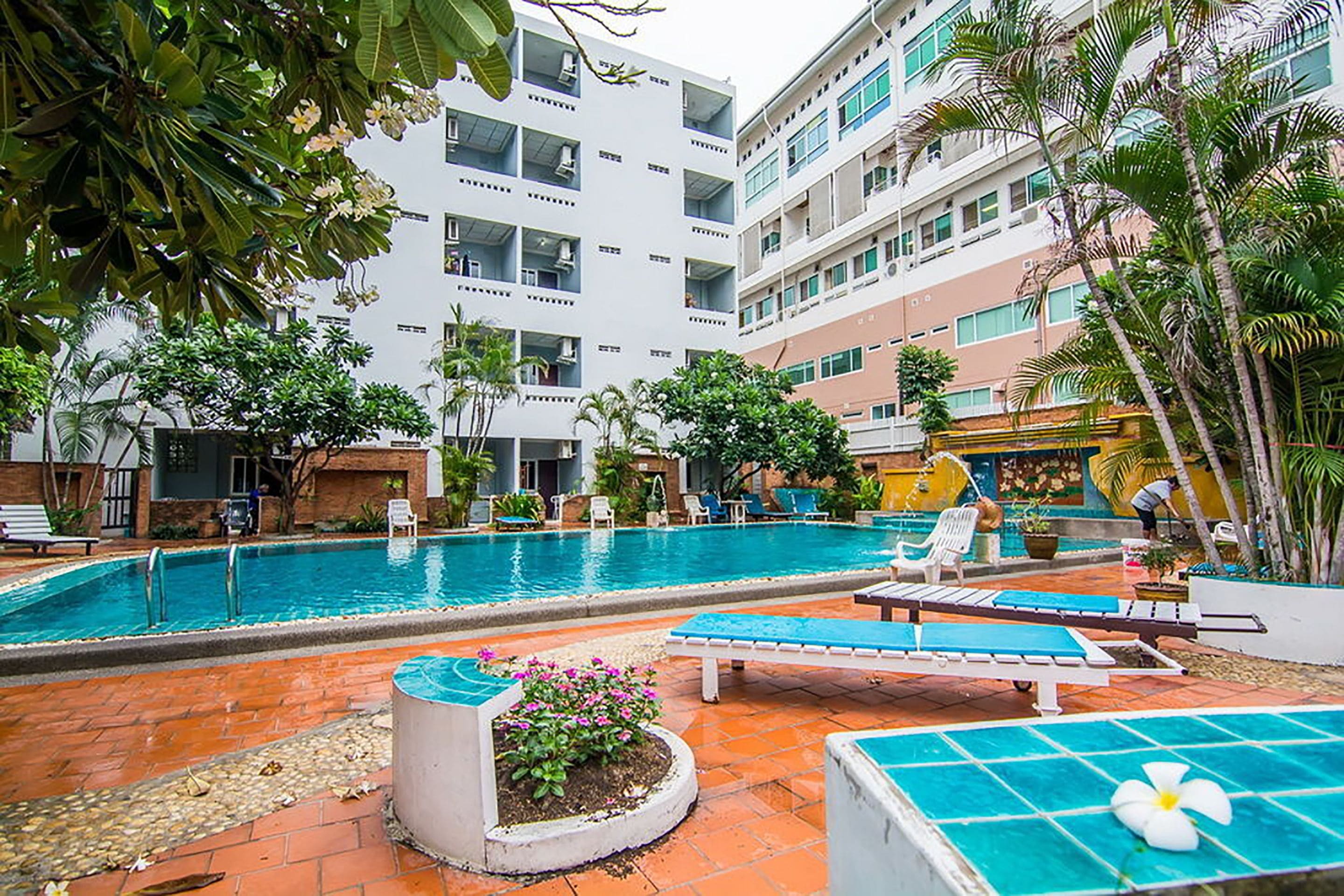 Un hotel con piscina, sillas de descanso y jardín.