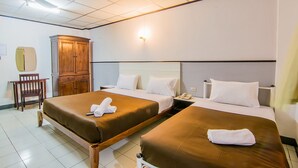 A hotel room with two beds, a wooden wardrobe, a desk, and a chair. - Sutus Court 3 (Pattaya)