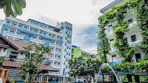 A swimming pool with a statue, surrounded by buildings and greenery. - Sutus Court 3 (Pattaya)