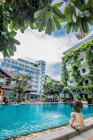 A swimming pool with a statue, surrounded by buildings and greenery. - Sutus Court 3 (Pattaya)