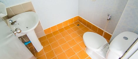 Un baño con lavamanos blanco, inodoro y zona de ducha.