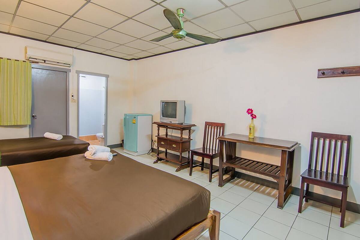 A hotel room with two beds, a television, a small table, and a chair.