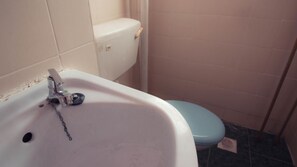 A bathroom with a white sink, a blue toilet, and a tiled floor.