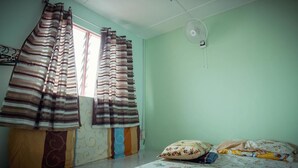 Una habitación con cama, almohadas, ventilador y cortinas.