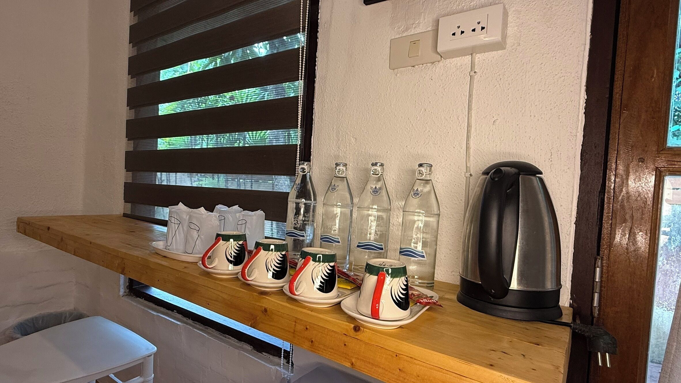 A wooden shelf with various items including glassware, bottles, and a kettle.