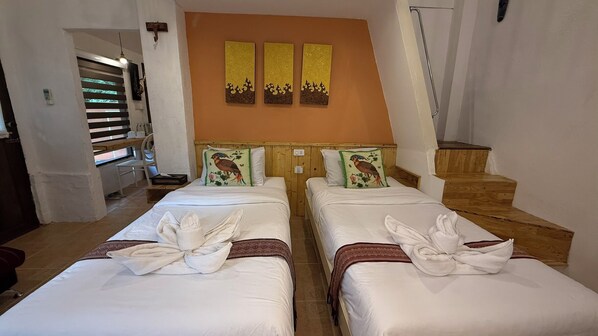 A hotel room with two beds, each with a towel and pillow. There is a wooden headboard, a wall-mounted artwork, and a staircase. - Pai Vintage Garden Resort (Pai)