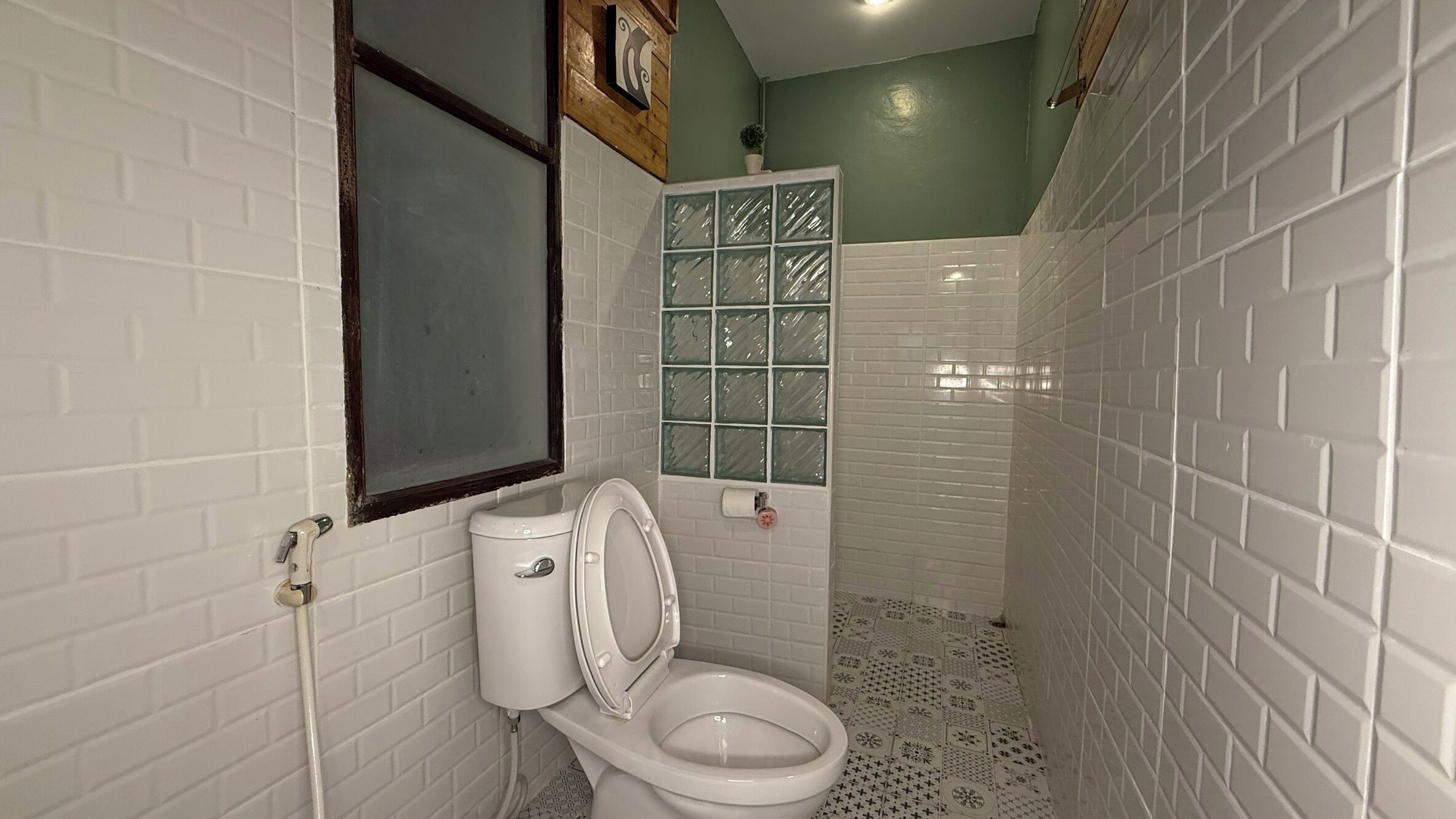 A small, narrow bathroom with white subway tiles, a white toilet, and a glass shower enclosure.