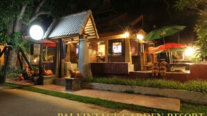 Un bâtiment traditionnel thaïlandais, doté d’un toit en tuiles, d’un petit porche et d’une enseigne.