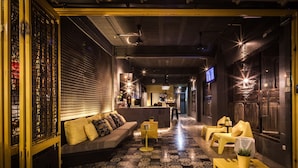 Un interior moderno con un sofá, sillas amarillas, suelo estampado y una zona de bar.