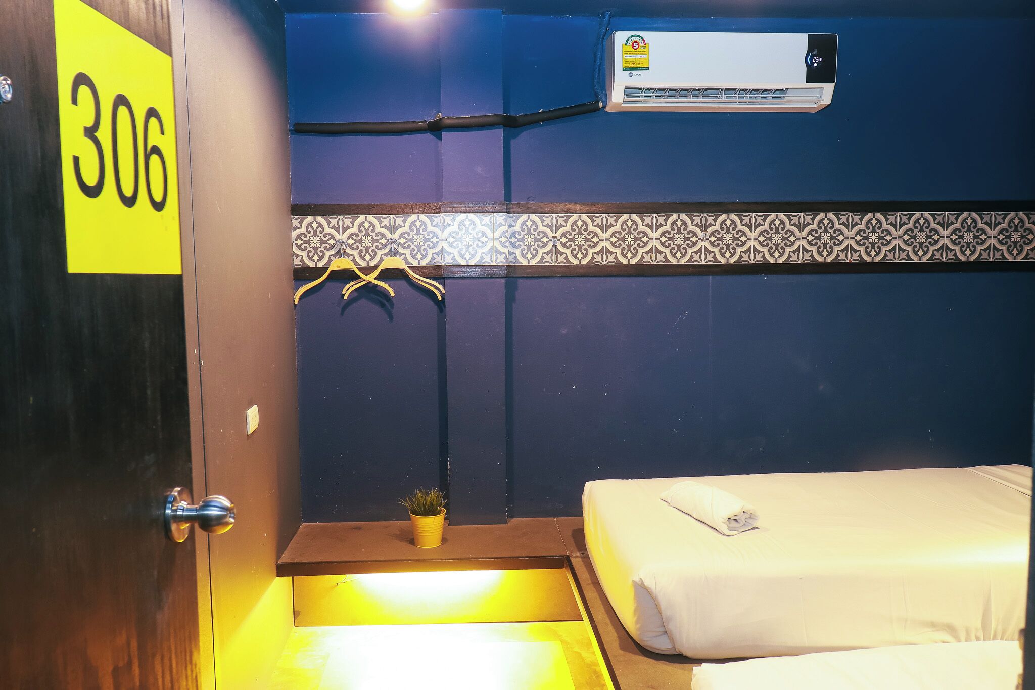 Een hotelkamer met een bed, een airconditioning, een kleine plant en een handdoek op het bed.