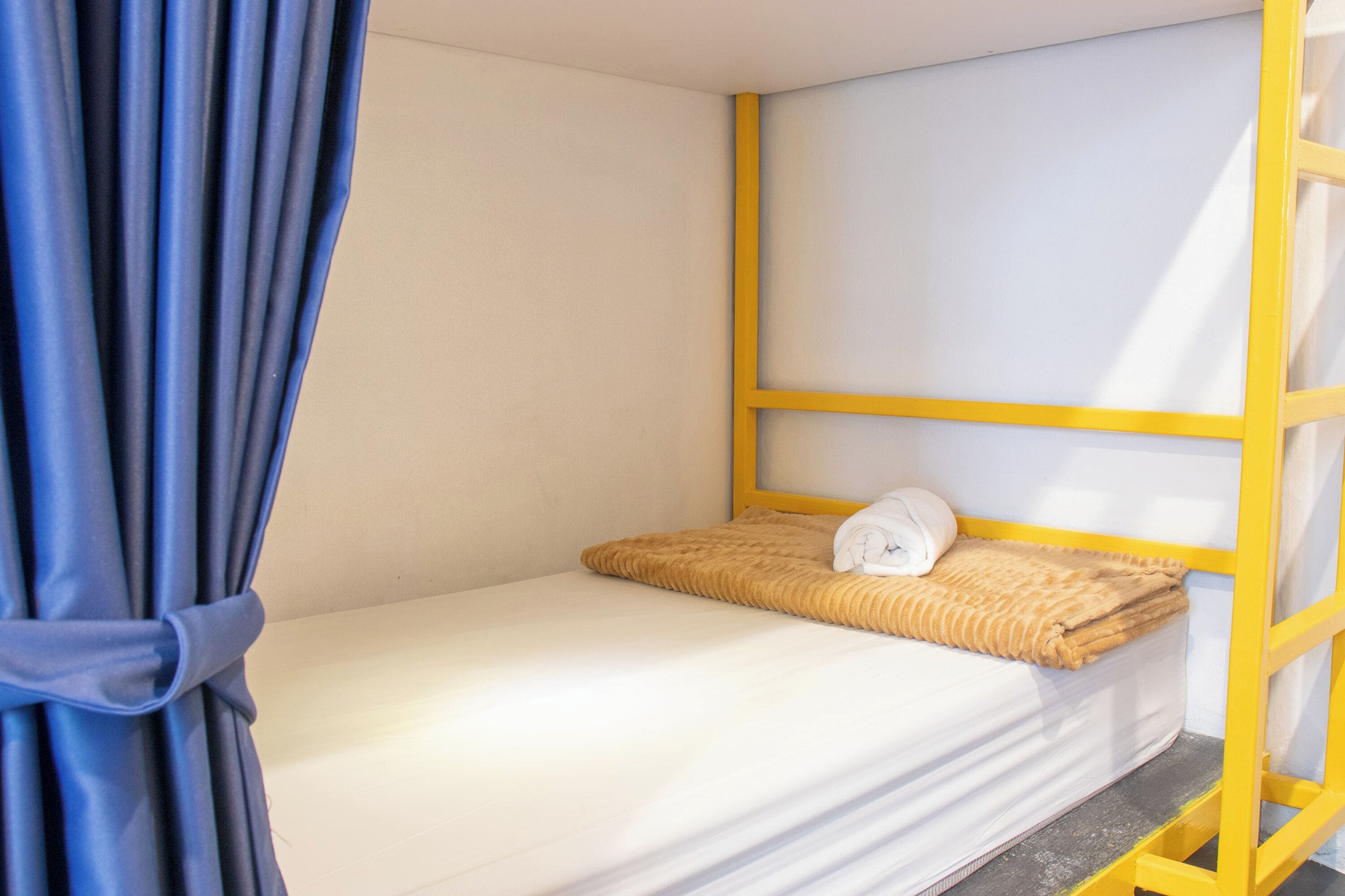 Una cama individual con cabecera, una manta y una almohada.