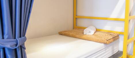Una cama individual con cabecera, una manta y una almohada.