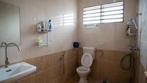 A bathroom with a toilet, sink, and shower. There are shelves with toiletries and a window above the toilet. - Holidayhome 188 Taman Sejati Suria (Sitiawan)