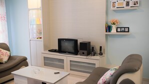 Ein Wohnzimmer mit Fernseher, Lautsprechern, Couchtisch und einer Couch.
