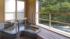 A hot spring bath area with a view of a forested river.