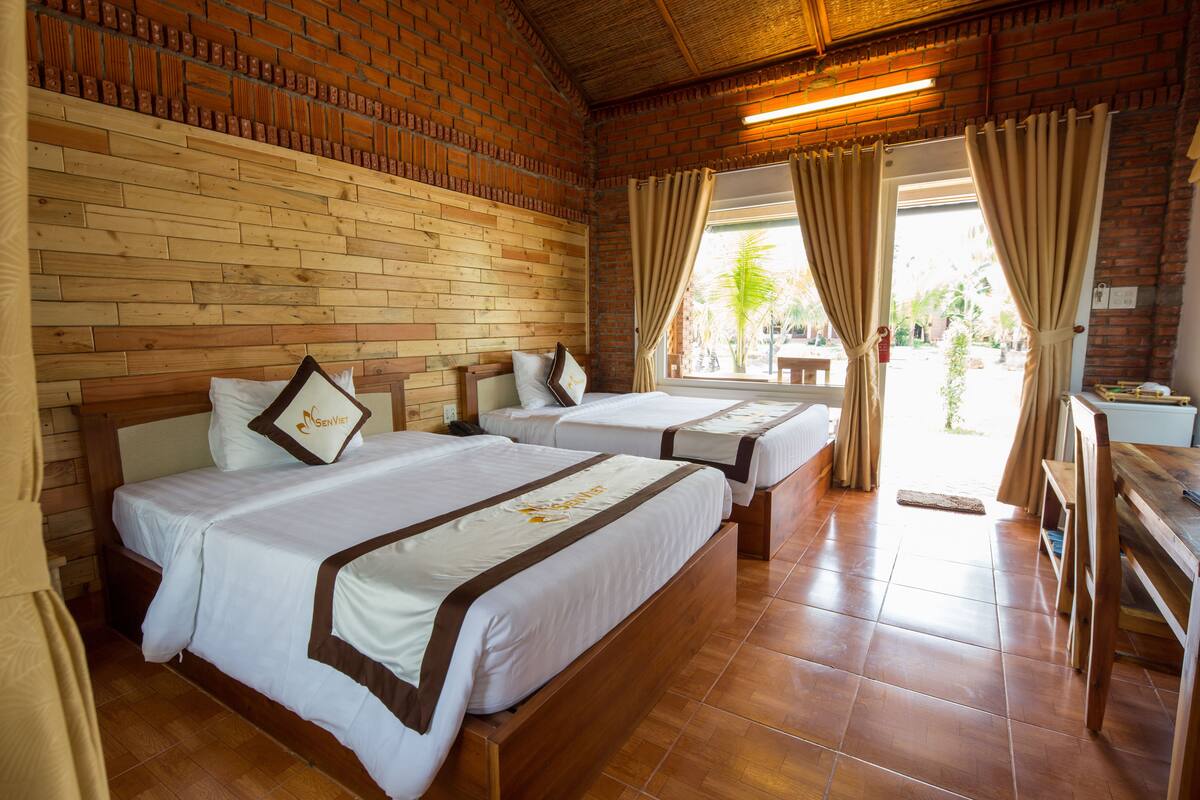 Een hotelkamer met twee bedden, houten hoofdborden en een bakstenen muur.