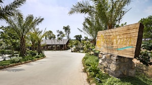 A sign for a village named "ASEN VILLAGE" with a stone base, surrounded by lush greenery and palm trees. - Sen Viet Phu Quoc Resort Sport & Spa (Phu Quoc)