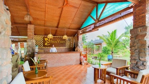 A restaurant with a brick counter, wooden furniture, and a view of greenery. - Sen Viet Phu Quoc Resort Sport & Spa (Phu Quoc)