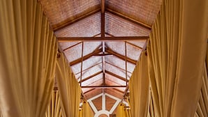 A banquet hall with high ceilings and a rustic wooden ceiling. Tables are arranged in rows with beige curtains. - Sen Viet Phu Quoc Resort Sport & Spa (Phu Quoc)