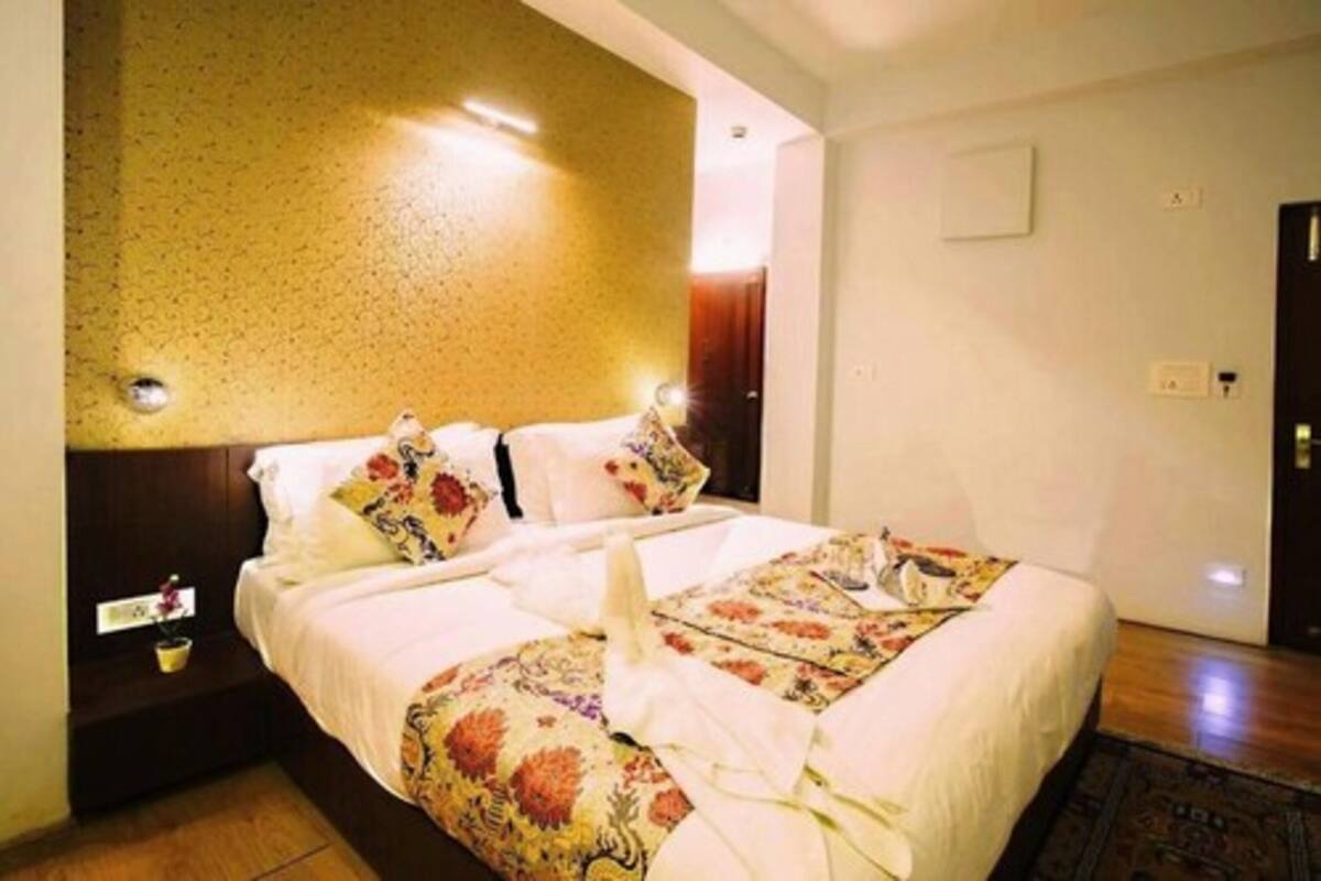 A hotel room with a large bed, a nightstand, a wall-mounted light, and a door.