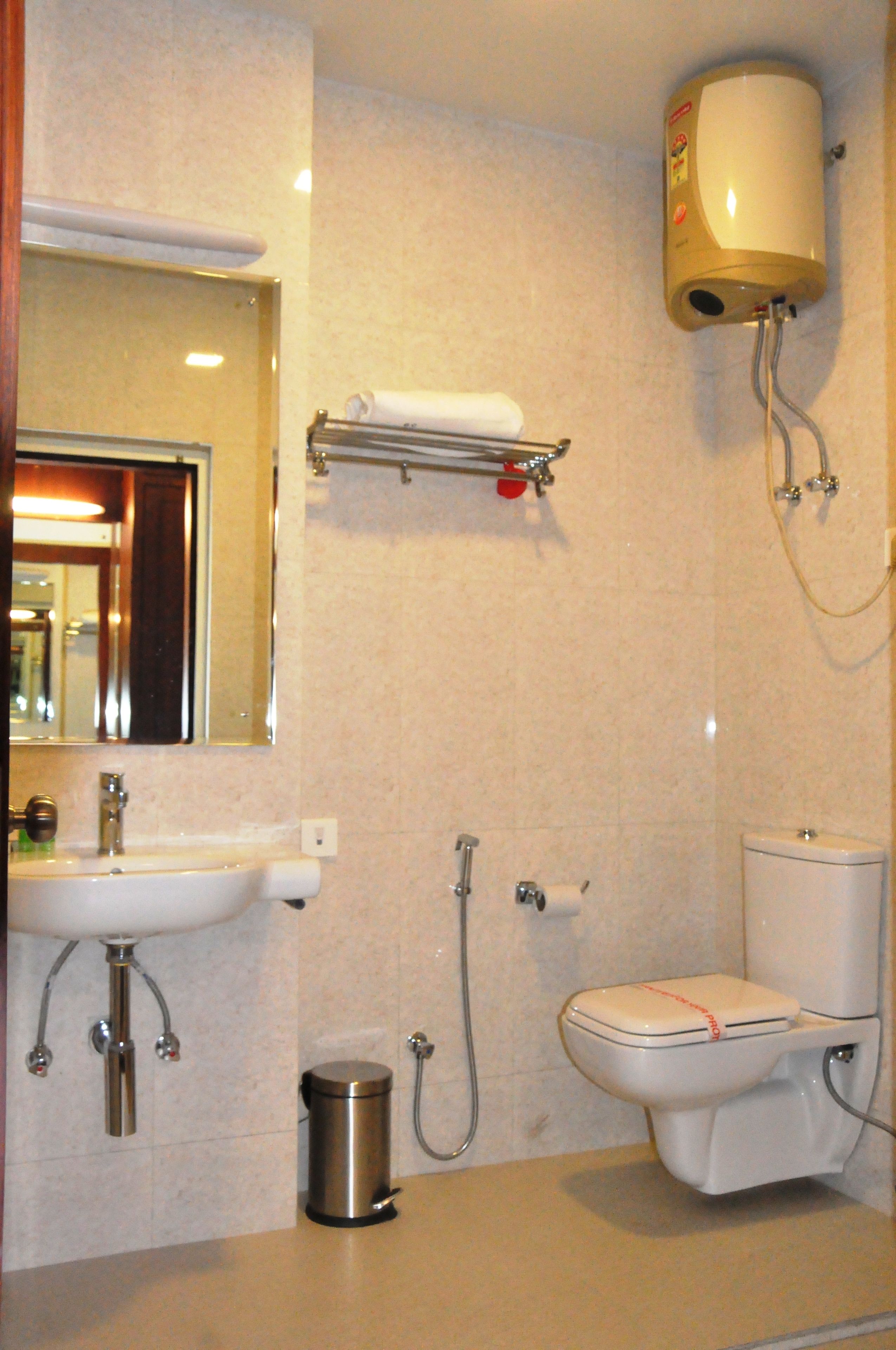 A bathroom with a sink, mirror, toilet, and a wall-mounted heater.