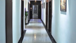 A long, narrow hallway with a polished floor, recessed lighting, and framed artwork on the walls. - The Golden Crest (Gangtok)