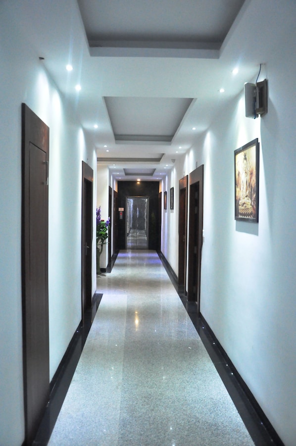 A long, narrow hallway with a polished floor, recessed lighting, and framed artwork on the walls. - The Golden Crest (Gangtok)